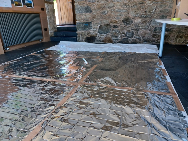 A large silver sheet covering trees inside a stone building
