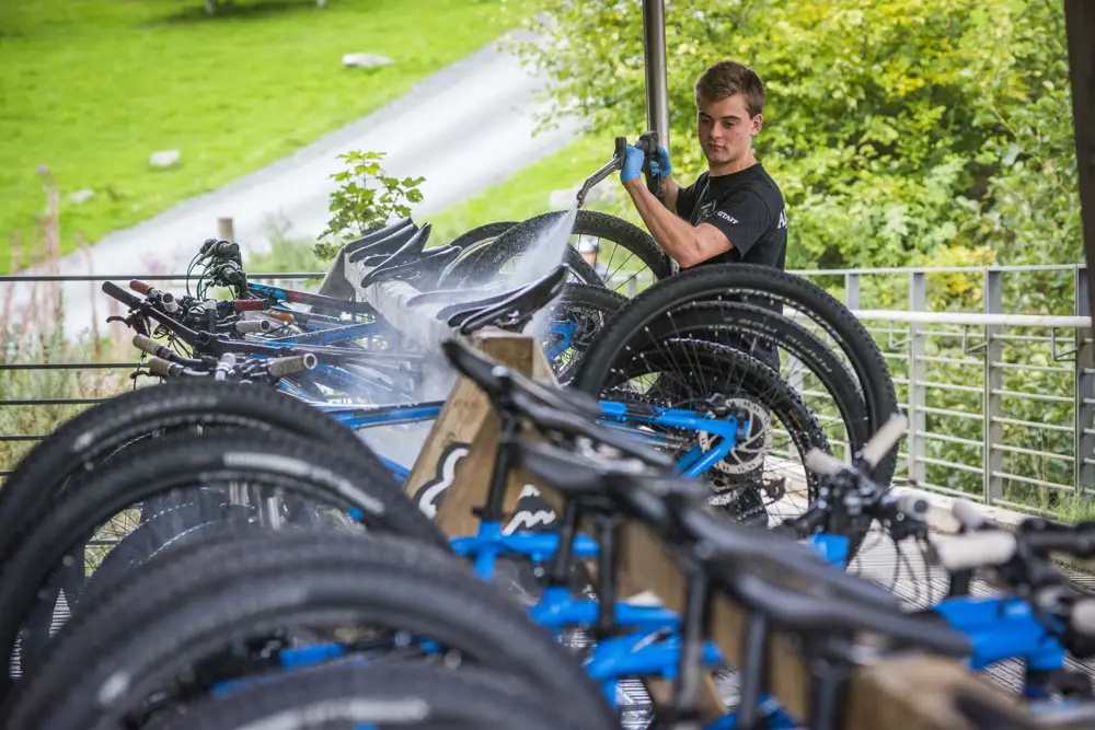 A man uses a pressure washer to clean bikes at Glentress