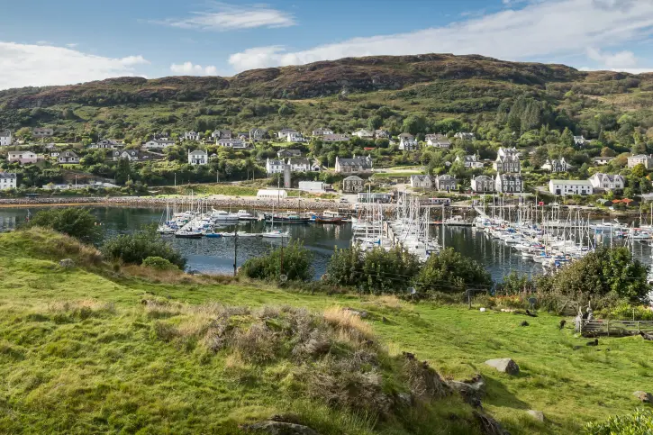 View across body of water to small town with wooded hill beyond