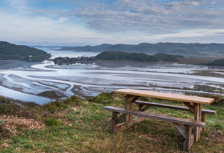 Aerial view over harbour and coast with a picnic table in the foreground