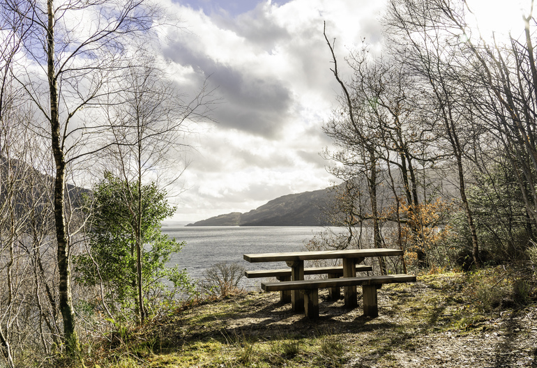 A wooden picnic table overlooking a loch