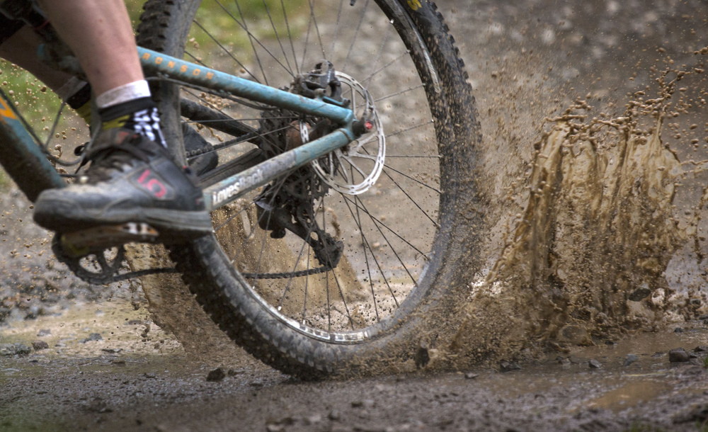 Close up of a mountain biker's rear wheel going through a puddle